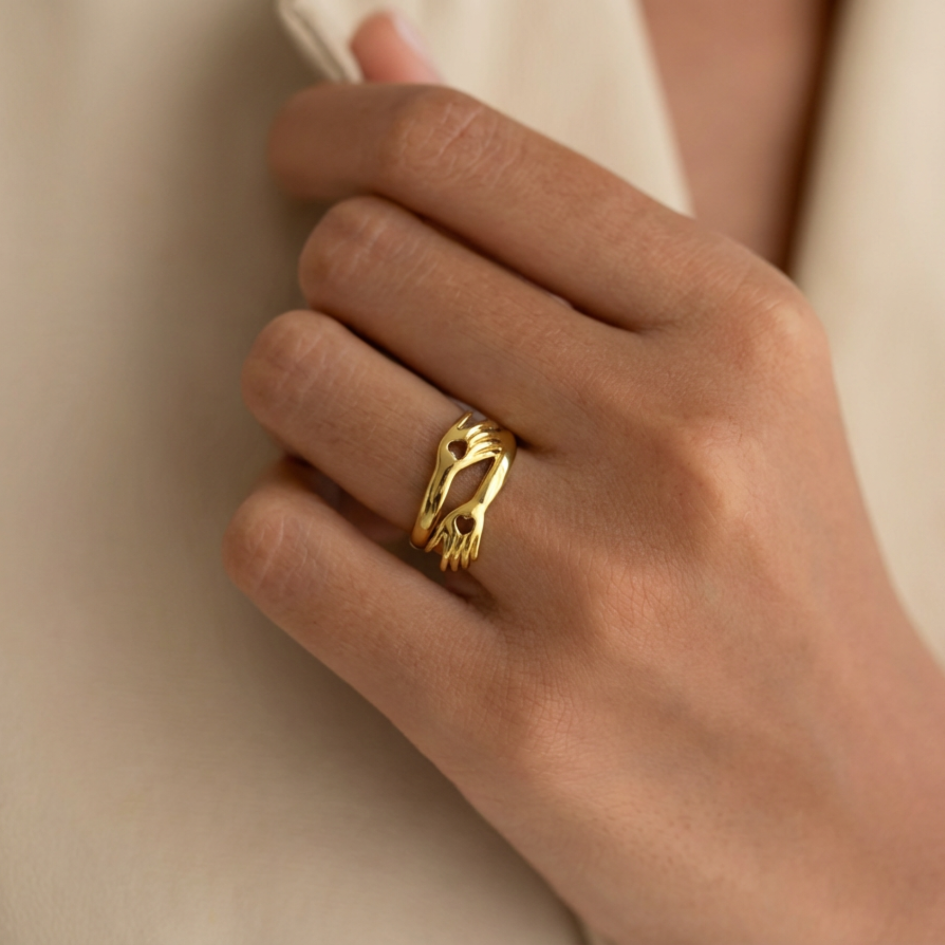 Gold ring on a person's finger against a neutral background
